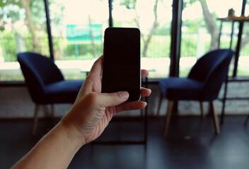 Close up of hands holding smart phone with blank copy space screen for your advertising text message or promotional content, hipster watching video on mobile phone during coffee break