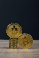 standing bitcoin on a stack of coins and wooden table over dark background