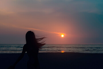 Women silhouette on beach during sunset.