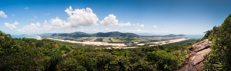 Fototapeta na wymiar Ultra wide panoramic landscape of the Ingleses and Mocambique dunes on a wonderful sunny day at Florianopolis, blue sky and mountains in the background. View from the top of Morro das aranhas. 