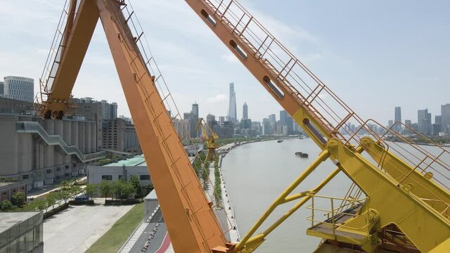 Drone flying through the crane around river with Shanghai city skyline. Aerial view of downtown cityscape. Business economy and industry concept b-roll footage of Shanghai China Lujiazui in background