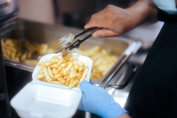 Professional Cook Putting French Fries in a Plastic Food Container