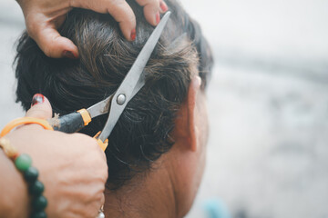 Fototapeta premium Old woman cutting her husband hair by herself.