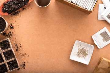 Lettuce seeds and other vegetable seeds in small envelopes with biodegradable peat pots and a shovel with potting soil on a raw surface with copy space