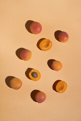 Ripe apricots with sunny shadows on pastel orange background. Summer food. Top view, flat lay, vertical
