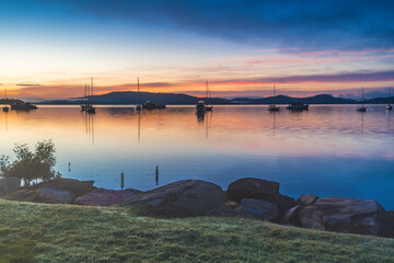 Sunrise waterscape with boats, light cloud and fog