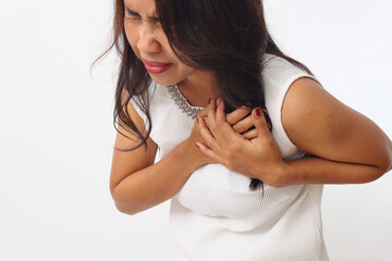 Close up photo of asian woman over isolated white background having a pain in the heart or chest...