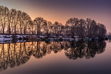 Fototapeta premium Reflection of houseboats and trees on bank of Jhelum River, Jammu and Kashmir, India