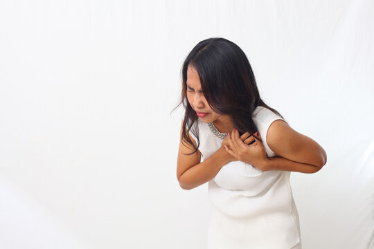 Close up photo of asian woman over isolated white background having a pain in the heart or chest pain or heart attack