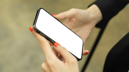 Female hand holding smartphone with mock-up screen while relaxed sitting in cafeteria