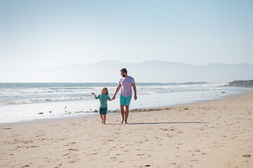 Dad and child having fun outdoors. Father and son walking on summer beach. Dad and child holding hands and walk together.