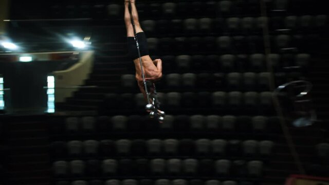 Acrobatic man flying around upside down on rotating performance at the circus arena