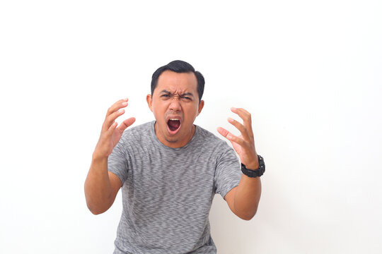 Asian man shouting frustrated with rage, hands trying to strangle, yelling mad. Isolated on white background with copyspace