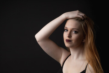 Portrait of beautiful young woman with hand in hair on the black background Horizontally. 