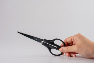 Hand holding black office stationery scissors cutting on white background isolation
