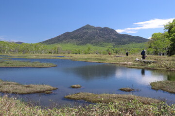尾瀬/6月。　まだ水芭蕉が咲き残る初夏の尾瀬ヶ原。山、空が写る池。逆さ燧（ひうち）