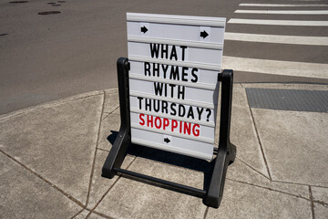Retail store promotion signage on the sidewalk. What rhymes with Thursday meme. Consumerism concept.