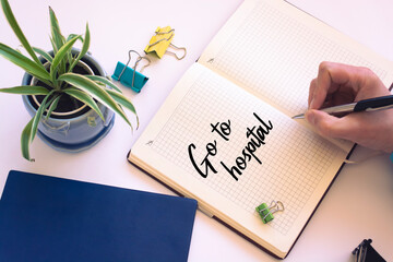 Fototapeta premium Closeup of a personal agenda setting an important date writing with pen. The words Go to Hospital written on a white notebook to remind you an important appointment.