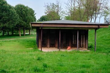 A wooden made tiny house in green grass in agricultural field or green park with green trees during spring time.