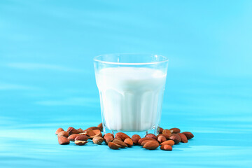 Almond milk with almond kernels. Alternative milk for vegetarians. Milk in a glass on a blue background.