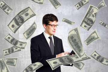 Attractive young european businessman with dollar bills on concrete wall background. Lottery winner concept.