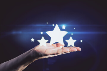 Hand holding glowing stars on blue background. Customer feedback and ranking concept