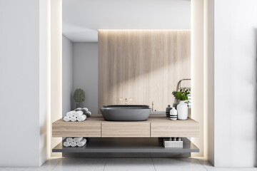 Black washbasin on wooden countertop, wooden partition, light walls and ceramic tales floor in sunny modern bathroom