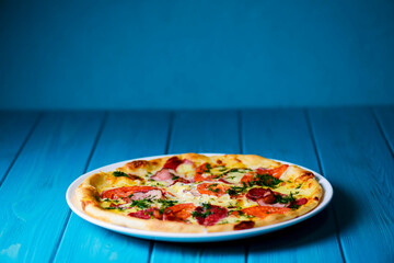 Cooked pizza on aged blue wooden surface background with copy space, side view.