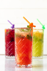 Three different refreshing lemonades on white wooden background