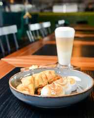 Close up of french style sweet crepes with soft cream served with a tall glass of coffee latte on a wooden table.