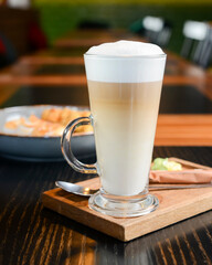 Close up of french style sweet crepes with soft cream served with a tall glass of coffee latte on a wooden table.