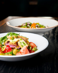 Buckwheat dumplings with fresh mushrooms and vegetable salad with cheese, fresh romatoes and cucumbers over black