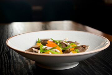 Buckwheat dumplings with fresh mushrooms served on a white plate over black background.