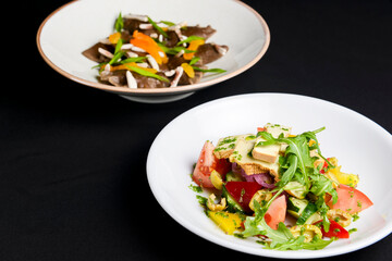 Buckwheat dumplings with fresh mushrooms and vegetable salad with cheese, fresh romatoes and cucumbers over black