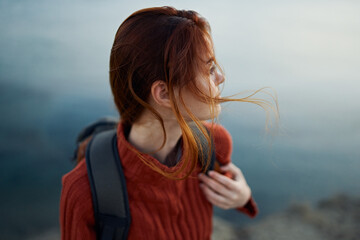 woman with backpack in mountains outdoors near the sea turned back cropped view model