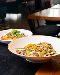 Buckwheat dumplings with fresh mushrooms and vegetable salad with cheese, fresh romatoes and cucumbers in restaurant.