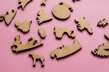 Wooden puzzle on a pink background. Puzzle pieces in the shape o