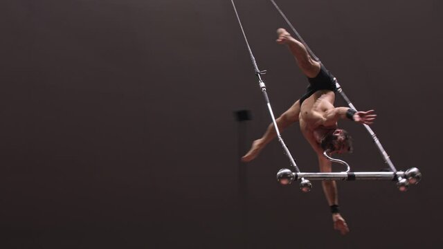 Acrobatic shirtless man giving out a performance upside down at the circus arena