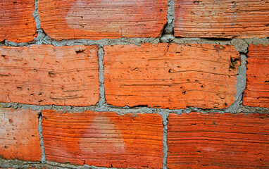 Red brick wall close-up. The texture of an old brick. Uneven, cracked surface.
