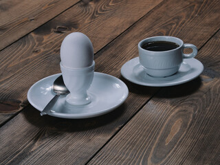 A cup of freshly brewed aromatic coffee and an egg on a stand