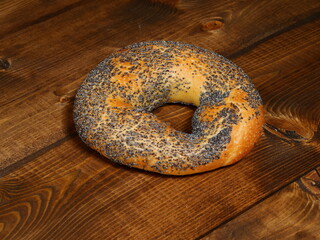 Fresh bagel with poppy seeds on a wooden table