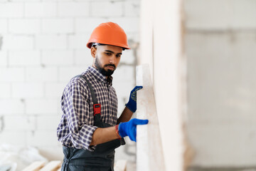 Builder at facade plastering work during industrial building with putty knife float