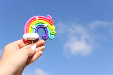 woman hand holding colorfull rainbow against blue sky.