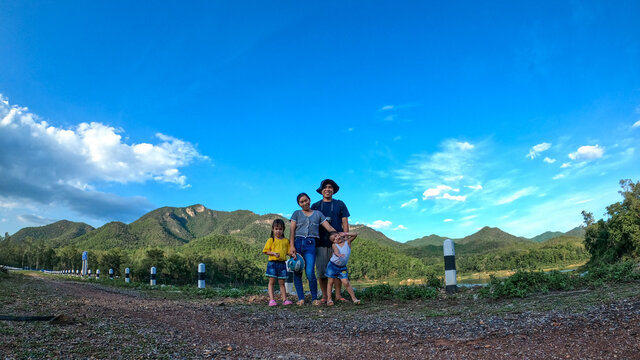 Happy family taking pictures among nature, mountains and sky on a clear summer vacation.