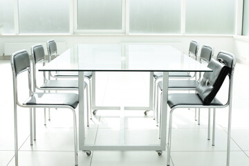 Glass table chairs and briefcase in office space