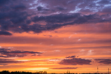 Golden sunset over the city. Thunderclouds illuminated by the setting sun