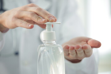 Doctor with a stethoscope in a clinic treats his hands with an antiseptic. Close-up