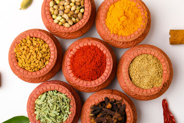 Indian spices collection, dried colorful condiment, nuts, pods and seeds and another spices in clay bowls.