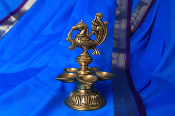 Indian traditional bronze oil lamp in the form of a bird on a blue sari background. Metal diya. traditional Indian religious ceremony of Hindus. Diwali