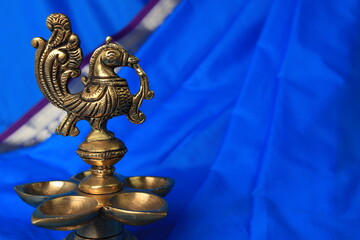 Indian traditional bronze oil lamp in the form of a bird on a blue sari background. Metal diya. traditional Indian religious ceremony of Hindus. Diwali